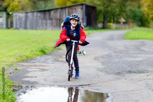 Fototapeta Naklejka Na Ścianę i Meble -  Cute preschool kid boy riding on scooter to school