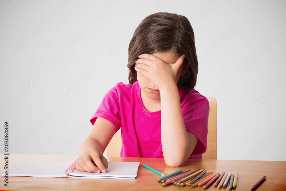 Cute pupil working at her desk against grey vignette Cute pupil working at her desk against grey vignette