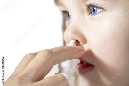 Mother using nose spray to cure her little girl Close up. photo