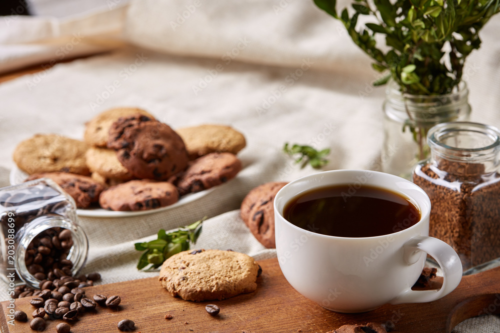 Coffee cup, jar with coffee beans, cookies over homespun tablecloth, selective focus, close-up, top view Coffee cup, jar with coffee beans, cookies over homespun tablecloth, selective focus, close-up, top view