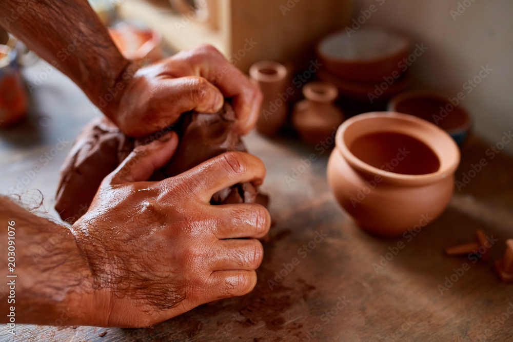 Hands of male potter molding a clay in pottery workshop, close-up, selective focus Hands of male potter molding a clay in pottery workshop, close-up, selective focus