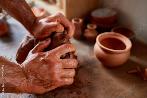 Hands of male potter molding a clay in pottery workshop  close-up  selective focus
