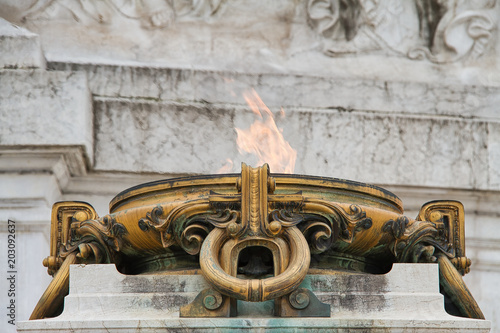 A cauldron with a flame in front of white marble.