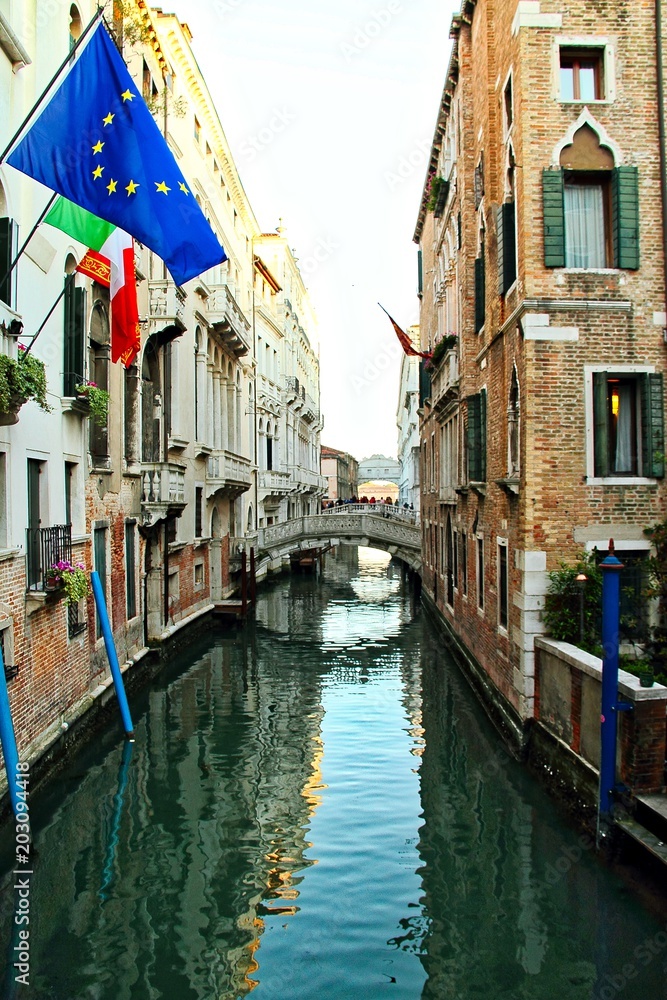 An empty canal in Venice, Italy with a bridge.