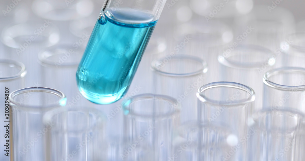 Science pipette with a drop of substance over laboratory test tubes Science pipette with a drop of substance over laboratory test tubes