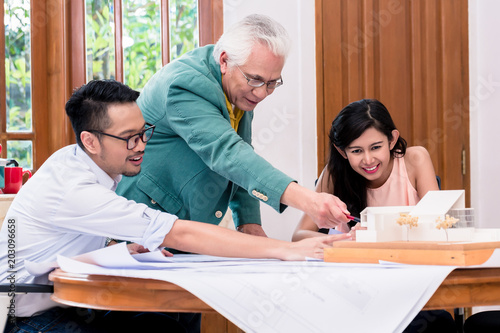 Successful senior architect congratulated by his younger colleagues in his office from home