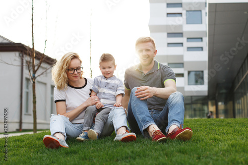 Portrait of happy young family having fun with their son on the green grass