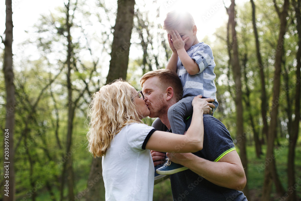 Mom and dad kiss while their little son closes his eyes Mom and dad kiss while their little son closes his eyes