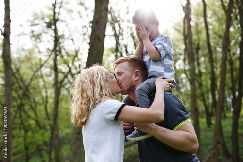 Mom and dad kiss while their little son closes his eyes