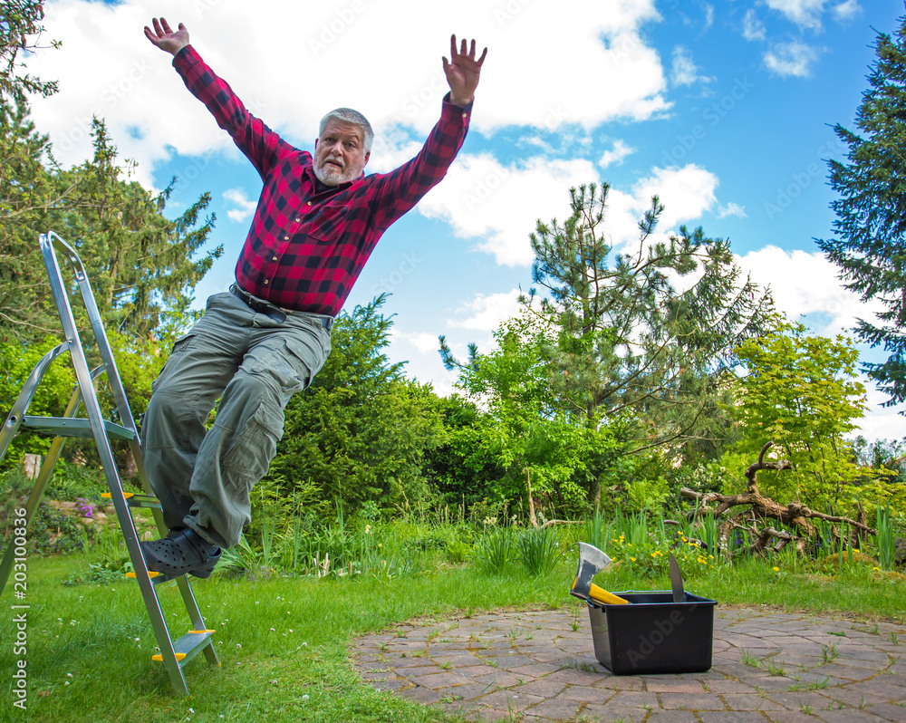 a man loses his balance and falls off a ladder Stock Photo