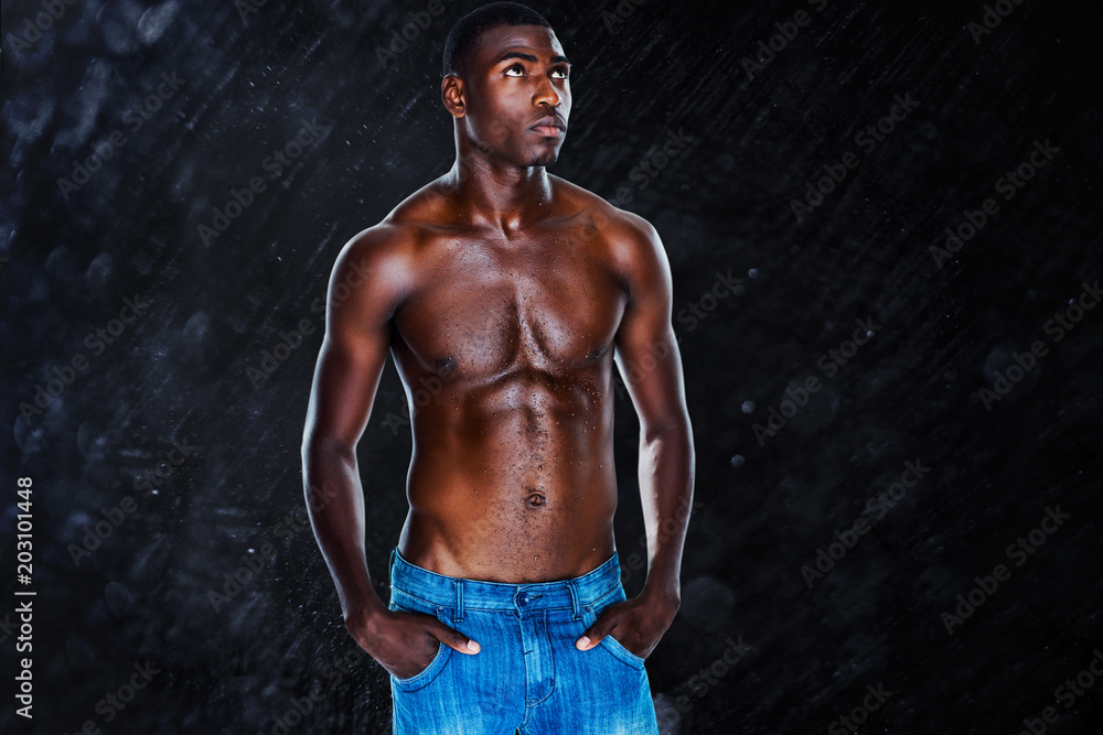 Fit shirtless young man against black background