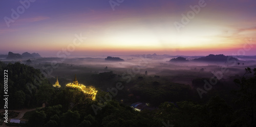 Beautiful sunrise with pagoda on the top of rock and tree with fog Panorama at Khao Na Nai Luang Dharma Park,Surat thani province,Thailand