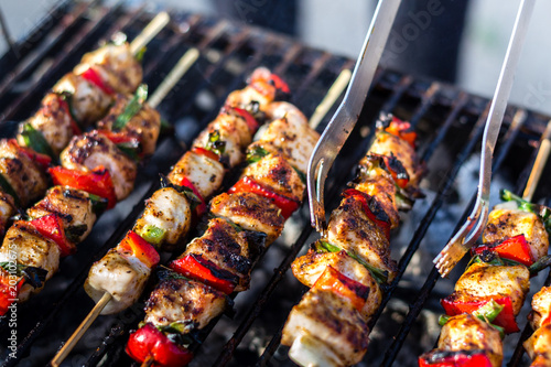 Close up pf delicious chicken breast on wooden skew with fresh vegetables, garlic, paprika fried on mangal barbeque grill