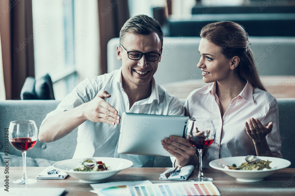 Fototapeta premium Smart man with tablet sits with young woman in cafe.
