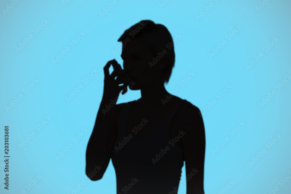 Person Using Inhaler Shadow Blonde woman taking her inhaler against blue background with vignette ...