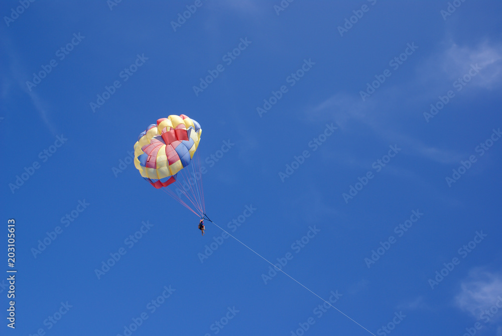Two people glide with a parachute against the blue sky. Selective focus Two people glide with a parachute against the blue sky. Selective focus