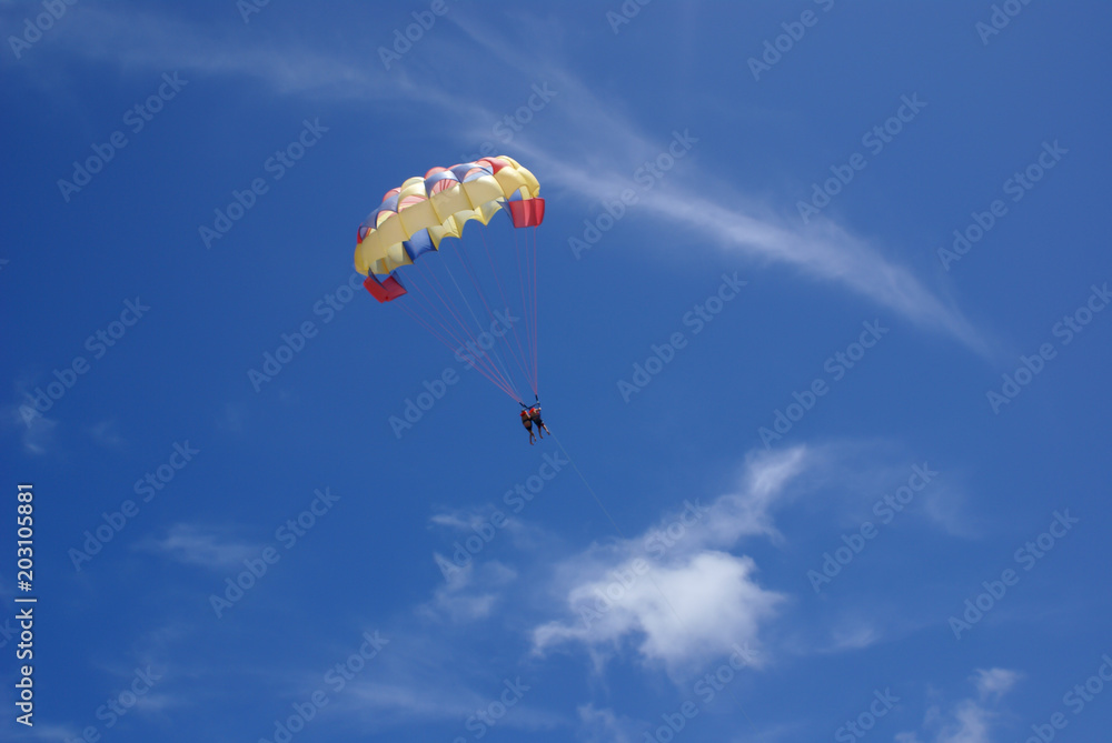 Two people glide with a parachute against the blue sky. Selective focus Two people glide with a parachute against the blue sky. Selective focus