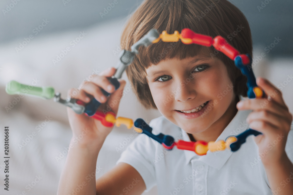 Cheerful kid sits with toy that develops logic. Educational toys. Cheerful kid sits with toy that develops logic. Educational toys.
