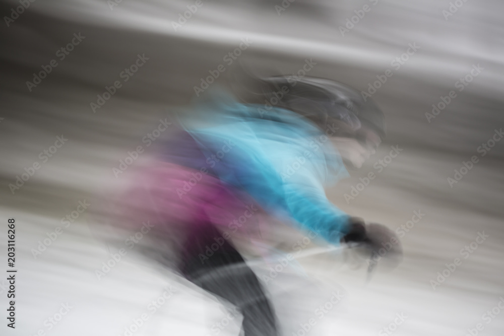 A fast skiing young woman in the bright colors is moving down to the hill to motion blurred shape resemble alien in famous film about exploring universe. Creative long time exposure sport photography.