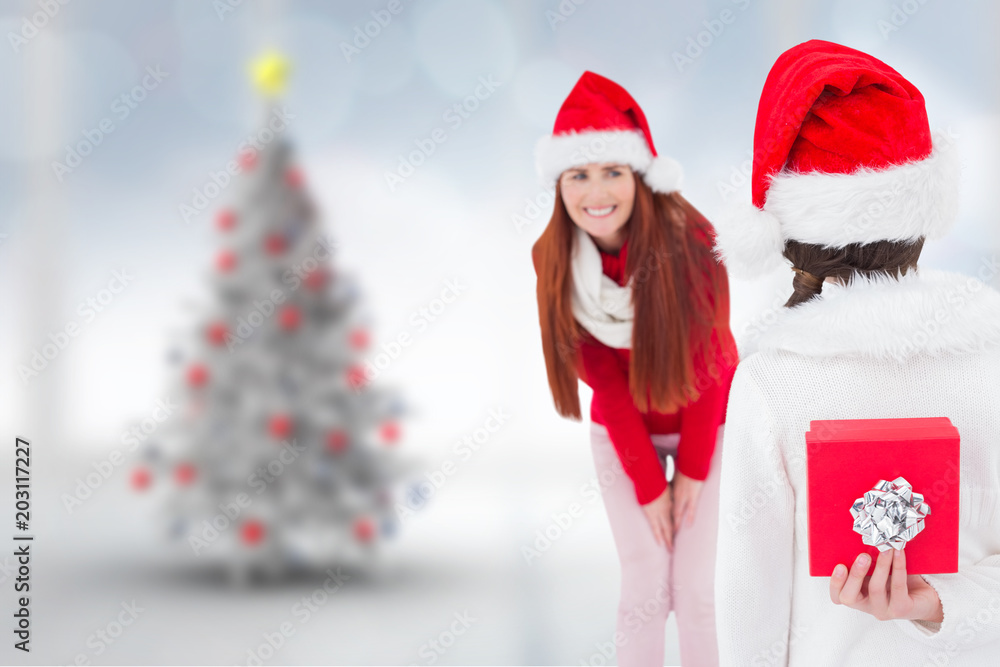 Mother and daughter with gift against blurry christmas tree in room Mother and daughter with gift against blurry christmas tree in room