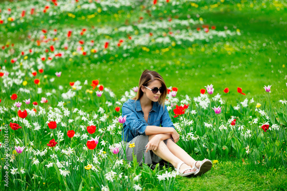 Young redhead girl sitting at tulips meadow in springtime garden Young redhead girl sitting at tulips meadow in springtime garden