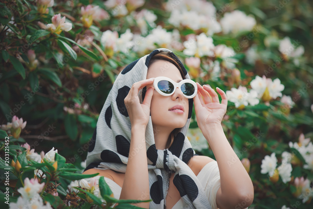 Young redhead girl in white shawl near flowers at springtime blossom garden. Young redhead girl in white shawl near flowers at springtime blossom garden.