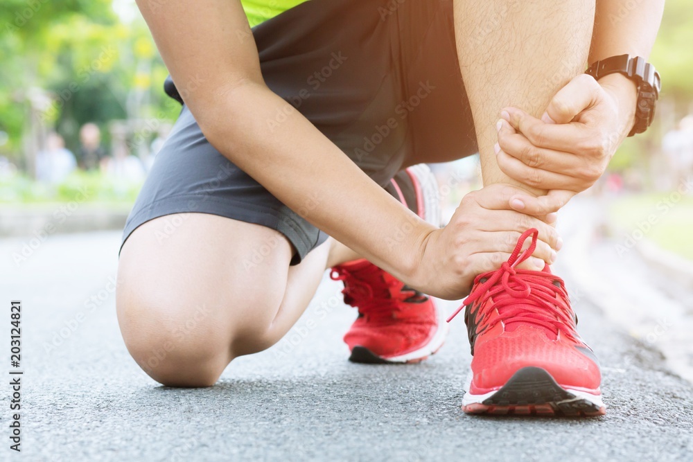 Runner touching painful twisted or broken ankle. Athlete runner ...
