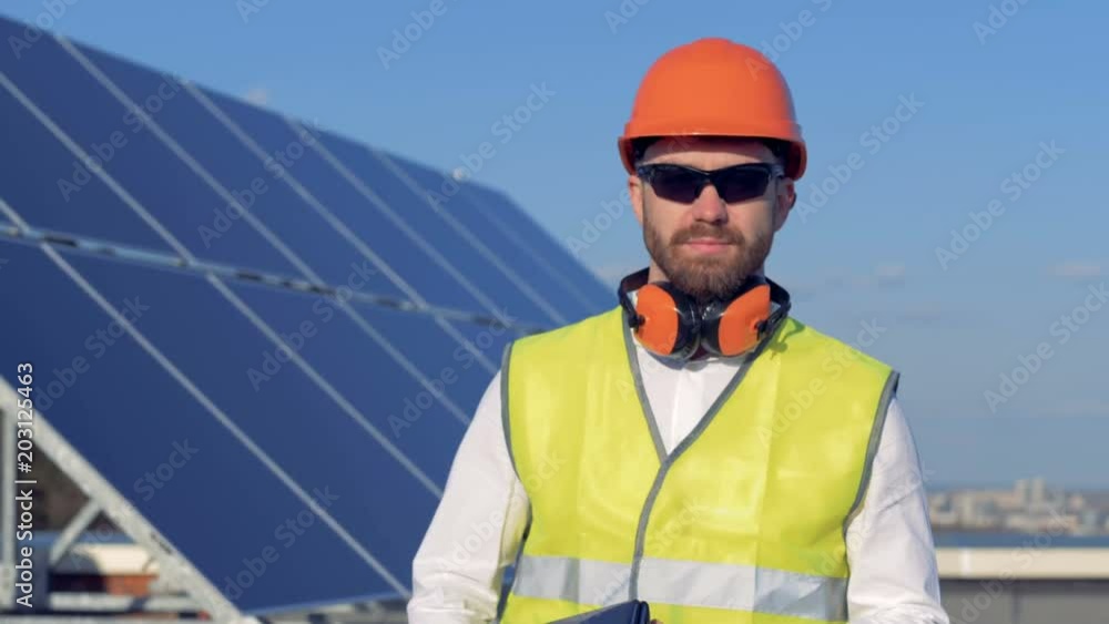 Professional engineer turn to camera and smiles, standing on the roof with a laptop. 4K. Professional engineer turn to camera and smiles, standing on the roof with a laptop. 4K.