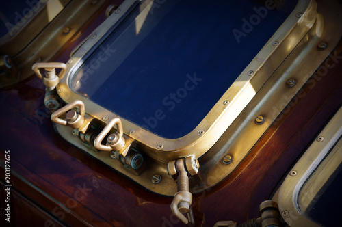 Ship window on wooden fone of an old ship. Technical aestetic. Dark colorfull background. Bronze details. photo