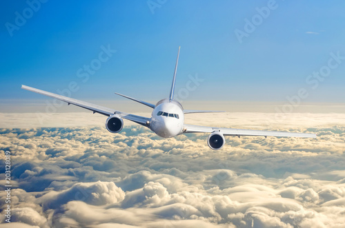 Passenger airplane flying at flight level high in the sky above the clouds and blue sky sunrise.