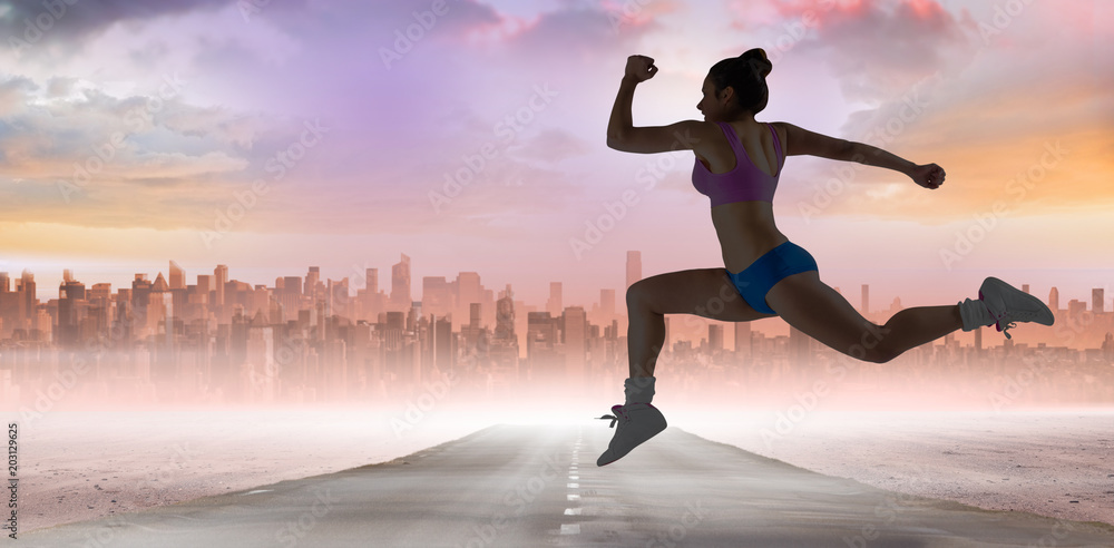 Fit brunette running and jumping against sun shining over city