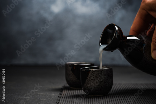 Quadro su tela Man pouring sake into sipping bowl
