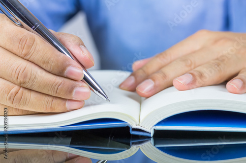 A man hand writing something on notebook