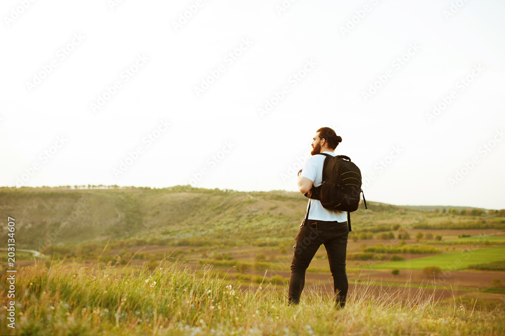 Hipster young man with backpack enjoying sunset on peak mountain. Tourist traveler on background valley landscape view mock-up.Retro filter effect, selective focus. Hipster young man with backpack enjoying sunset on peak mountain. Tourist traveler on background valley landscape view mock-up.Retro filter effect, selective focus.
