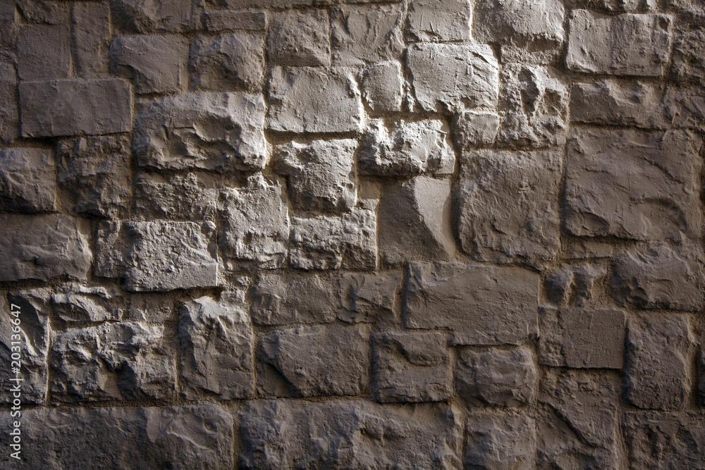Fototapeta premium A stone wall with a sunbeam. Texture of wild stone.