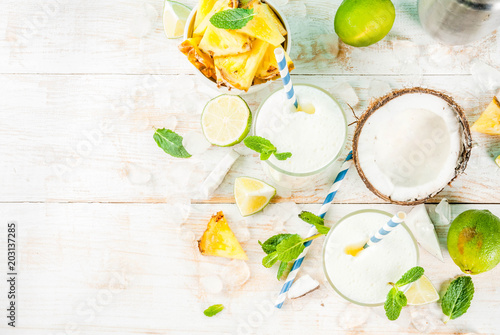 Tropical cocktail, pina colada, pineapple and coconut mojito or smoothies, with lime and mint, on a light blue background copy space