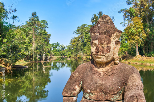 Stone statue of guardian Asura on the bridge that crosses the moat surrounding Preah Khan temple, Angkor, Cambodia © Alexey Pelikh