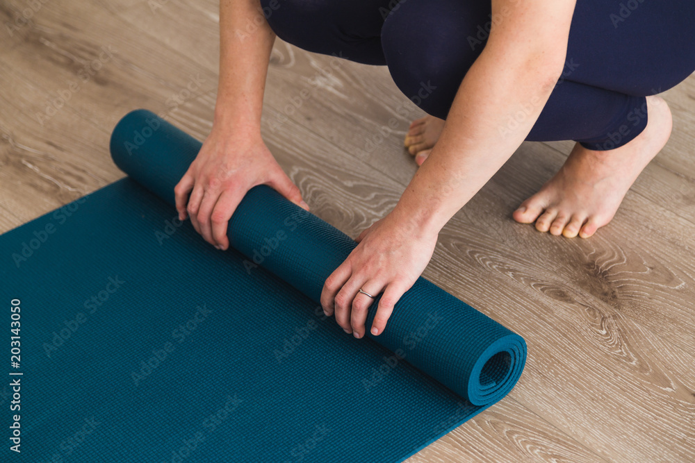 Woman unrolling yoga mat in a yoga studio Woman unrolling yoga mat in a yoga studio