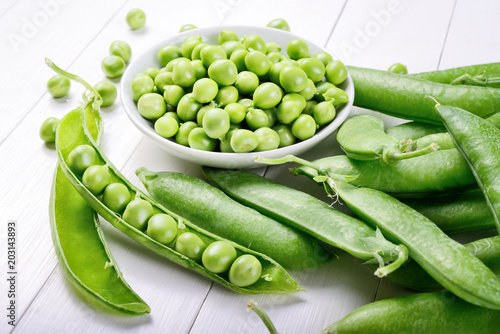 Shelled and unshelled peas on white wood background