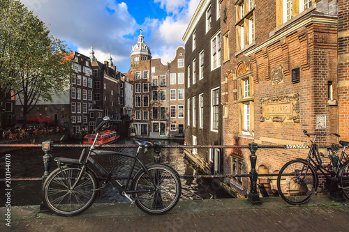 Bicycles parked on a canal bridge in Amsterdam with view of St. Nicolas Church, Netherlands 
