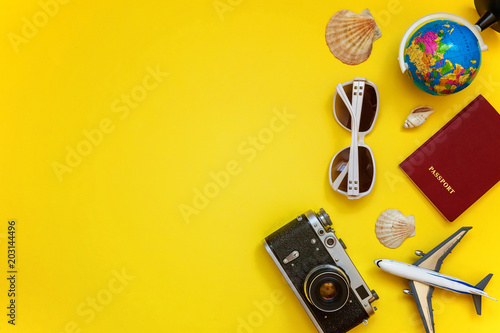 Flat Lay with plane  vintage camera  passport  globe  sunglasses and shell on yellow colourful trendy modern fashion background. Vacation travel summer weekend sea adventure trip concept