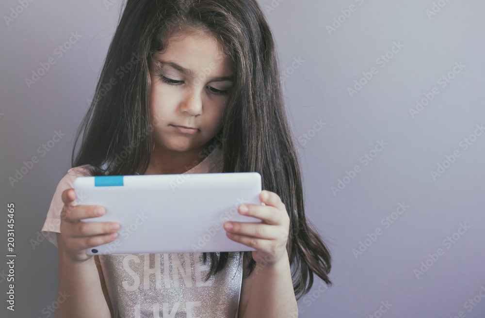 leisure, childhood, technology and people concept - cute little girl child with gadget. Toned image. leisure, childhood, technology and people concept - cute little girl child with gadget. Toned image.