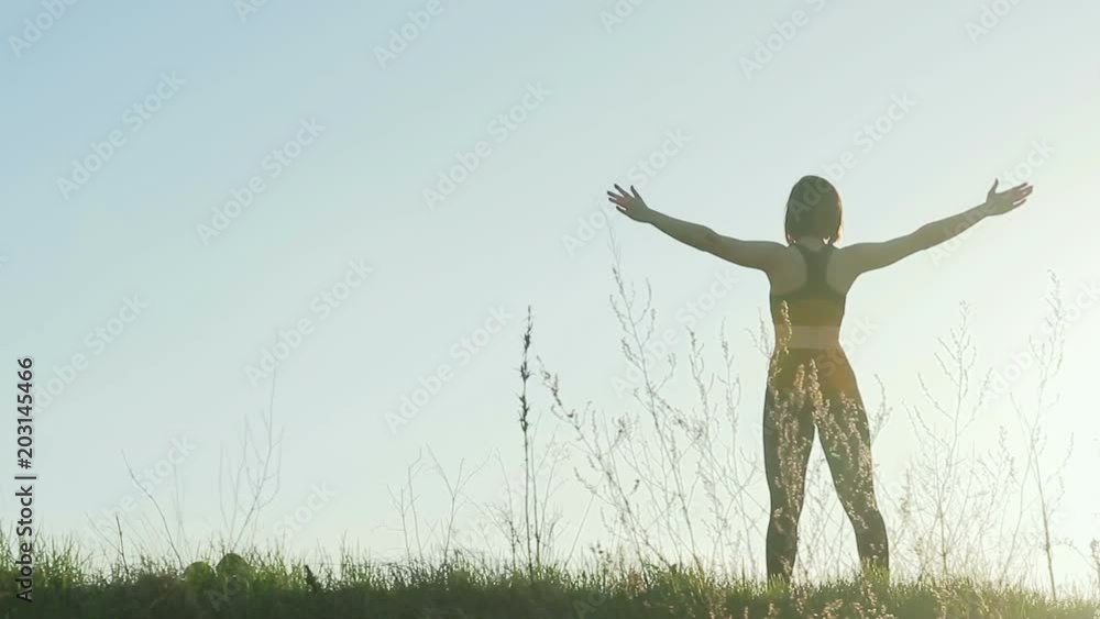 Young pretty sportswoman is engaged in fitness in nature. Silhouette of a girl doing exercise against the sky. General plan. Steadicam shot Young pretty sportswoman is engaged in fitness in nature. Silhouette of a girl doing exercise against the sky. General plan. Steadicam shot