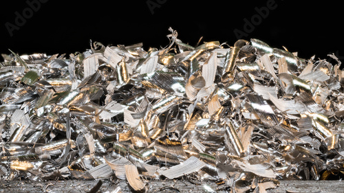 Tangle of glossy metal shavings. Close-up of the pile of manufacturing metallic chips on black background. Idea of industry, mechanical engineering, machining. Great depth of field.