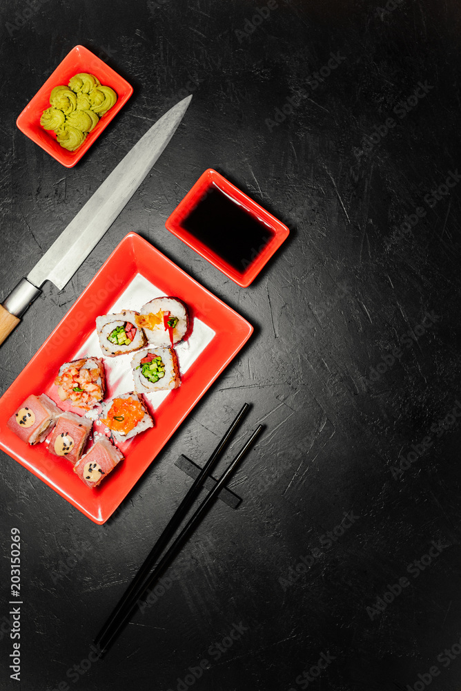 Obraz premium Set of sushi, Japanese knife, chopsticks and on dark stone table. Top view with copy space. Wasabi, soy sauce. Sushi on a table.