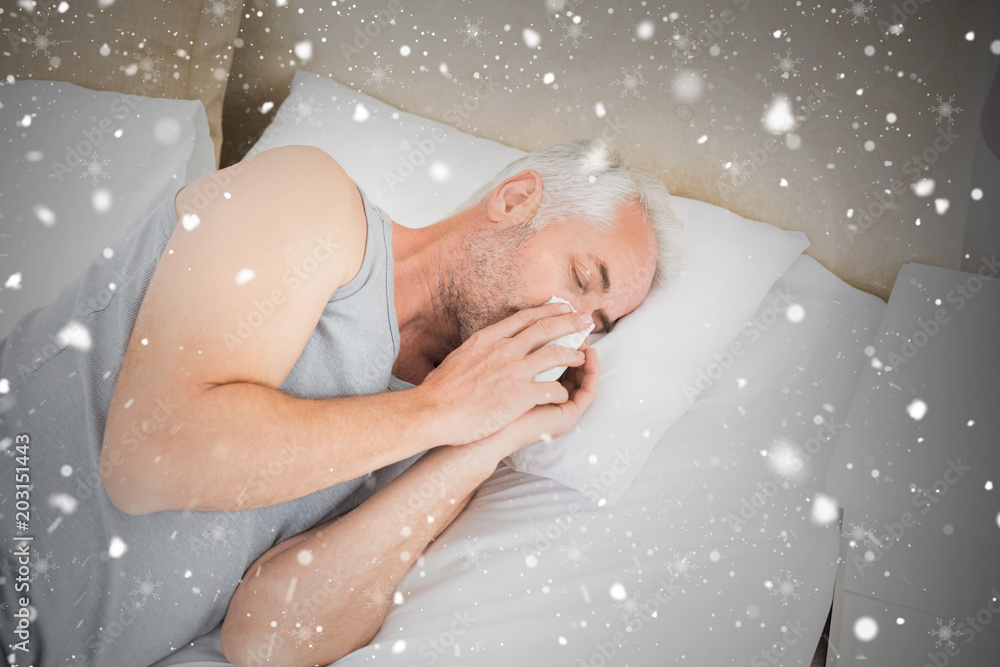 High angle view of a man suffering from cold in bed against snow falling