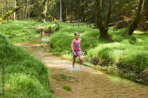 Child cute blond girl playing in the creek. Summer children fun. 