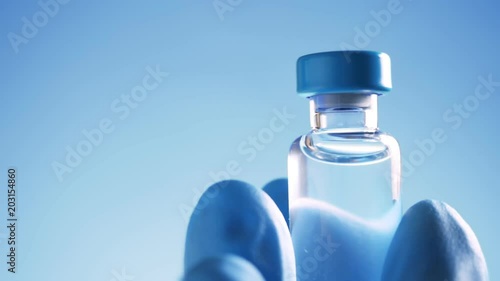 Doctor in blue latex gloves holding glass vial with medicine photo