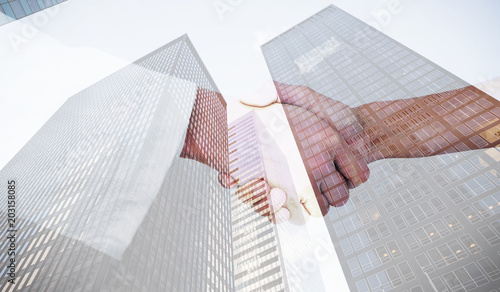 Extreme closeup of a doctor and patient shaking hands against skyscraper