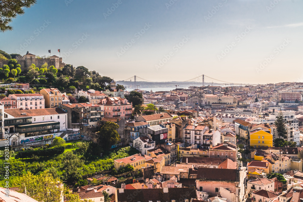 Panoramic image of the city of Lisbon, Portugal. Some buildings in the center of the city, the castle of San Jorge and the famous bridge of April 25 in the background above the Tejo river.